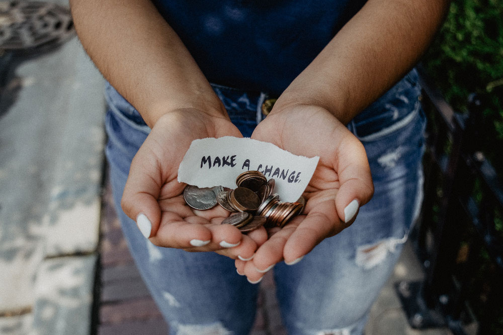 A women holding coins in her hand and a piece of paper that says make a change