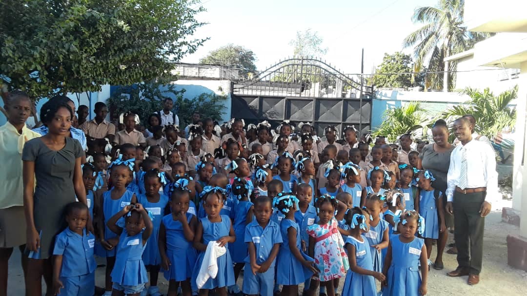Students in Haiti posing with their teachers at the school gates